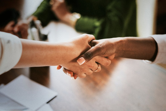 Two people shaking hands across a desk after a screening consultation