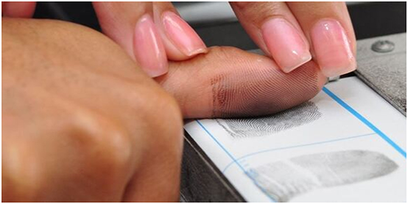 Rolled ink fingerprint being taken on an FD-258 card